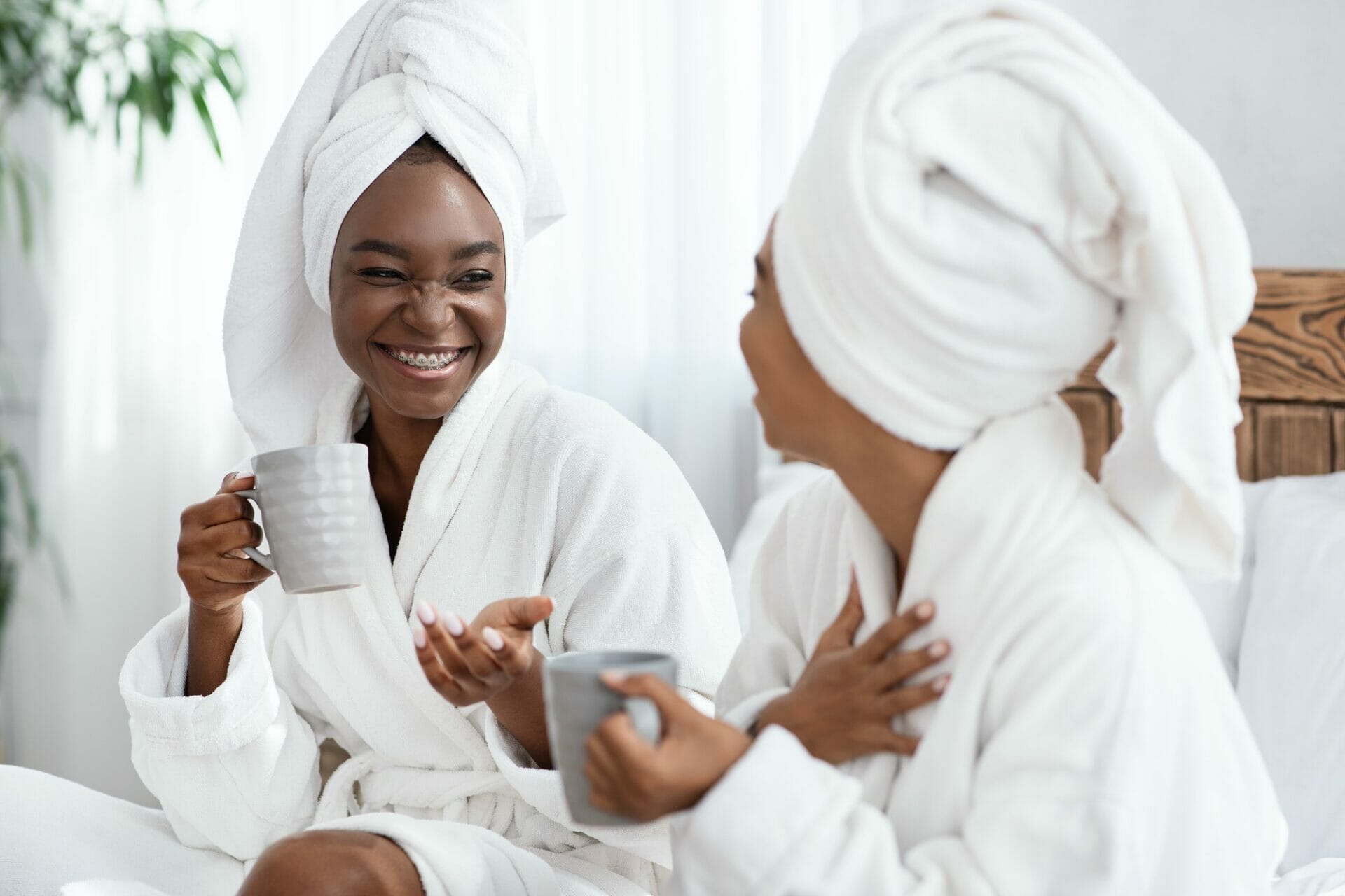 Two joyful black women joking while drinking tea